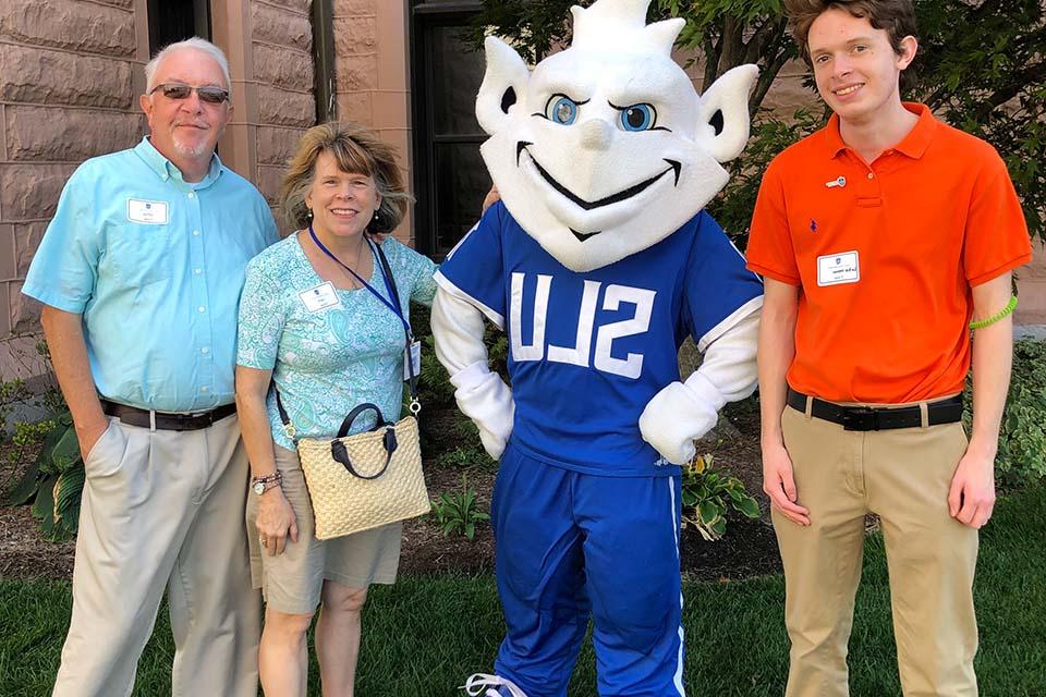 Three members of the Fister family pose for a photo with the Billiken.